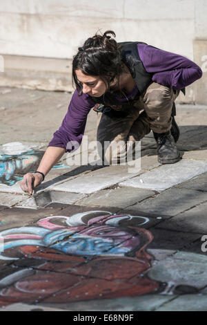 Ein weiblicher Streetart-Künstler tut bunte Bürgersteig Designs während des Karnevals an einem Fußgänger Hauptverkehrsstraße in Venedig. Stockfoto