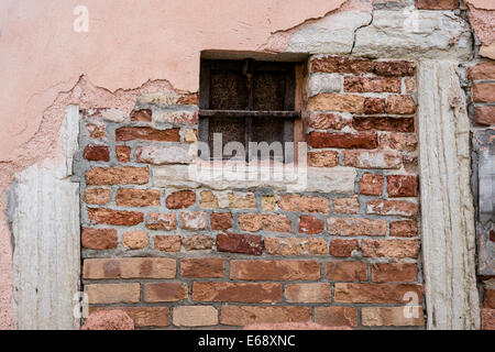 Detail der vergitterten Fenster und alte Ziegelwand mit läutenden Putz in Venedig. Stockfoto