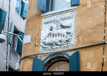 Reliefskulptur des Hl. Georg und der Drache über ein Fenster in einem alten Haus in Venedig. Stockfoto