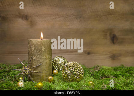 1. Advent: Goldene Kerze vor einem hölzernen Hintergrund. Stockfoto