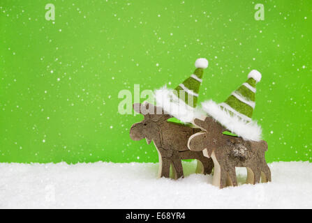 Paar zwei hölzerne Rentiere auf grünem verschneite Weihnachten Hintergrund. Idee für eine Weihnachts-Grußkarte. Stockfoto