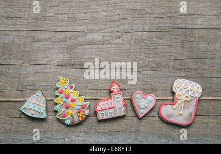 Vereisung Lebkuchen in Pastellfarben dekoriert auf einem hölzernen Hintergrund für Weihnachten. Stockfoto