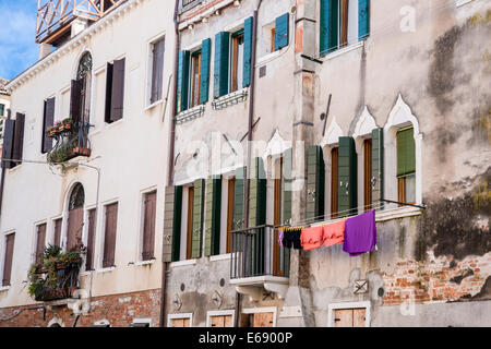 Alte Häuser entlang einer Seite Kanal von Venedig mit Wäscheständer auf einer Linie. Stockfoto