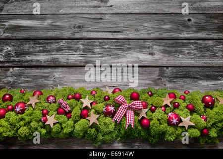 Aus Holz Weihnachten Rahmenhintergrund mit grünem Moos und rote Kugeln. Stockfoto