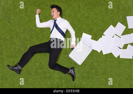 Junger Mann mit Aktentasche liegen auf dem Rasen Stockfoto