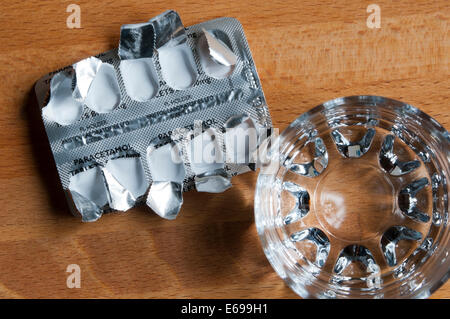 Leere Packung Paracetamol Tabletten und Glas Wasser auf den Nachttisch, von oben gesehen. Stockfoto