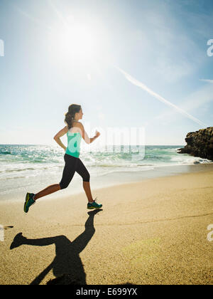 Kaukasische Frau läuft am Strand Stockfoto