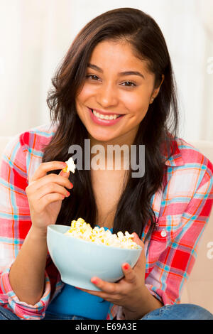 Hispanic Frau Essen Popcorn auf sofa Stockfoto