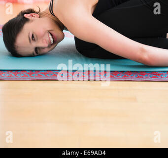 Kaukasische Frau lächelnd auf Yoga-Matte Stockfoto