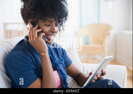 Schwarze Frau über Tablet PC auf Handy Stockfoto