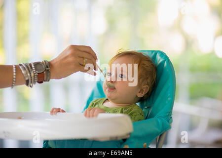 Kaukasische Mutter Baby im Hochstuhl füttern Stockfoto