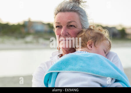 Kaukasische Frau, die die Enkel am Strand Stockfoto