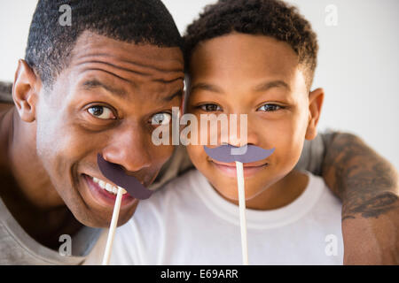 Vater und Sohn spielen mit gefälschten Schnurrbärte Stockfoto