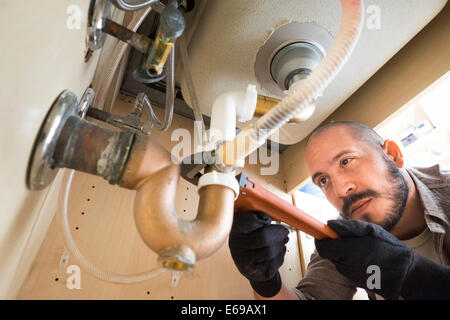 Hispanische Klempner Arbeiten unter Spüle Stockfoto