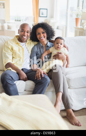 Familie lächelnd zusammen im Wohnzimmer Stockfoto