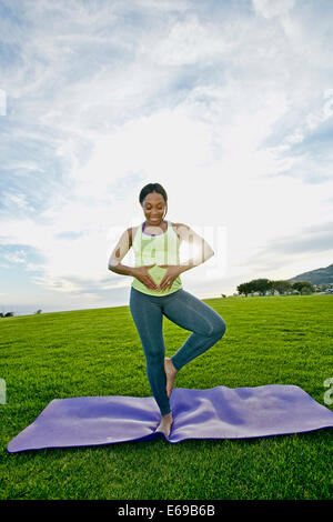 Schwangere Frau praktizieren Yoga im park Stockfoto