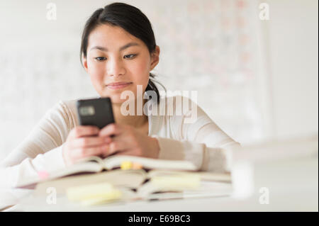 Gemischte Rassen Teenager-Mädchen mit Handy in der Klasse Stockfoto