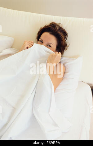 Frau, die versteckt unter der Bettdecke im Bett Stockfoto