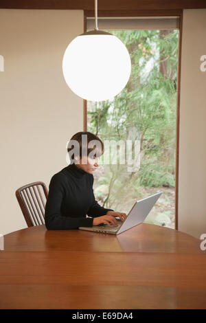 Kaukasische Frau mit Laptop am Tisch Stockfoto