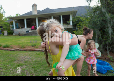 Mädchen tragen Schwester im freien Stockfoto