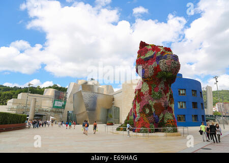 BILBAO, Spanien - 10. Juli 2014: Unbekannte Personen in der Nähe des Kunstwerks "Welpen" von Jeff Koons vor der berühmten Guggenheim Stockfoto