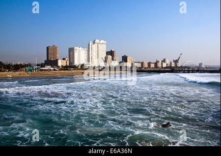 DURBAN, Südafrika - 23. Juli 2014: einsamer Surfer paddeln, aus Nordstrand gegen Skyline der Stadt in Durban, Südafrika Stockfoto