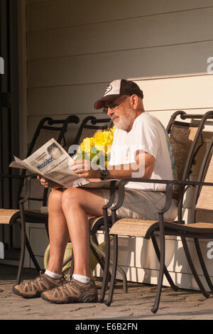 Reifer Mann auf Achterdeck seines Hauses lesen Morgen Zeitung, USA Stockfoto