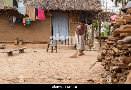 Indien, Meghalaya, Bajengdoba. Eine Frau fegt ihren Hof verpackt Schmutz. Region Ost Garo Hills. Stockfoto