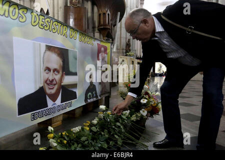 Sao Paulo, Brasilien. 19. August 2014. Ein Mann legt Blumen vor einem Bild des verstorbenen brasilianischen Präsidentschaftskandidaten Eduardo Campos, während einer Messe in seinem Gedächtnis in Sao Paulo, Brasilien, am 19. August 2014. Eduardo Campos, die dritte in Umfragen gelaufen war, starb bei einem Flugzeugabsturz letzte Woche. Bildnachweis: Rahel Patras/Xinhua/Alamy Live-Nachrichten Stockfoto