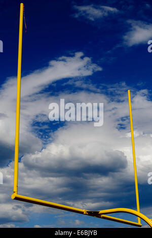 gelbe Fußball Torpfosten vor einem bewölkten blauen Himmel Stockfoto