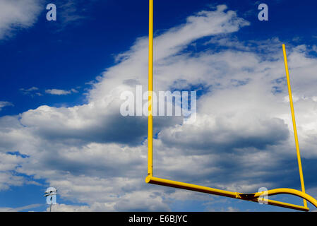 gelbe Fußball Torpfosten vor einem bewölkten blauen Himmel Stockfoto