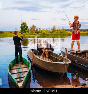 MINSK, BELARUS - 25 Juli: Belarussischer Kinder Angeln vom alten Boote bei Sonnenuntergang an einem Sommertag am 25. Juli 2013 in Minsk, Belaru Stockfoto