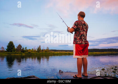 MINSK, BELARUS - 25 Juli: Belarussische Boy Angeln vom alten Boote bei Sonnenuntergang an einem Sommertag am 25. Juli 2013 in Minsk, Weißrussland Stockfoto