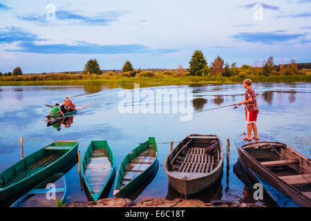 MINSK, BELARUS - 25 Juli: Belarussische Boy Angeln vom alten Boote bei Sonnenuntergang an einem Sommertag am 25. Juli 2013 in Minsk, Weißrussland Stockfoto