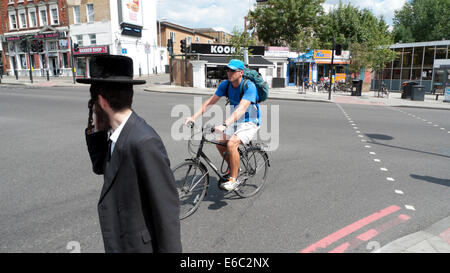 Radfahrer Mann auf dem Fahrrad und orthodoxen jüdischen Fußgängerampel die Straße in Stamford Hill London N16 UK KATHY DEWITT Stockfoto