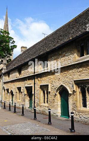 Armenhäuser mit St John the Baptist Church an der Rückseite Burford, Oxfordshire, England, Vereinigtes Königreich, West-Europa. Stockfoto