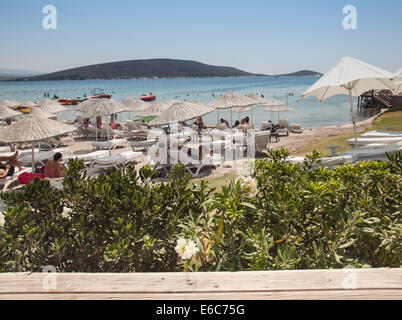 Cesme, Türkei, 2. August 2014: Touristenstrand auf der Cesme-Halbinsel in der Hochsaison durch Palmen gesehen. Stockfoto