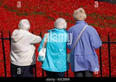 Drei Frauen, die sich Keramikmohn aus Blut ansehen, haben Lands and Seas of Red im Tower of London, Großbritannien, anlässlich des 100. Weltkriegs gesehen Stockfoto