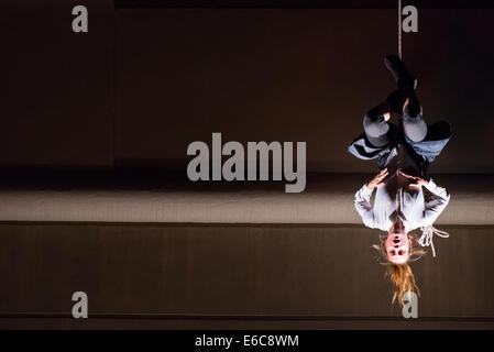 Frau kopfüber hängend an einer Schnur, Szene aus Vertigo - vertikale Tanz mit multimedia, Straße Theatershow Stockfoto