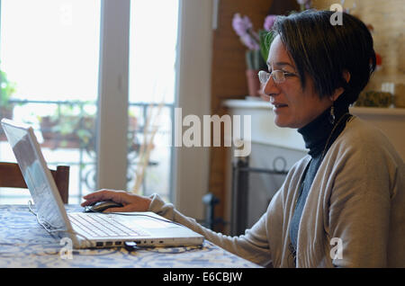 Frau mittleren Alters mit einem Laptop Computer, zu Hause Stockfoto