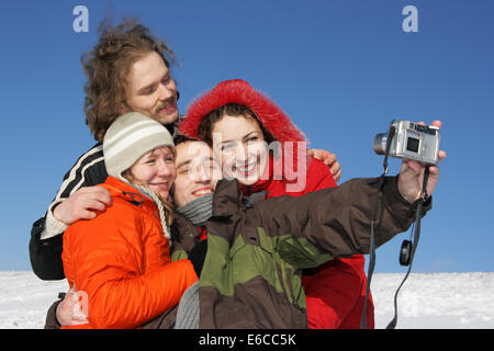 Vier Freunde, die unter einem Selbstbildnis im winter Stockfoto