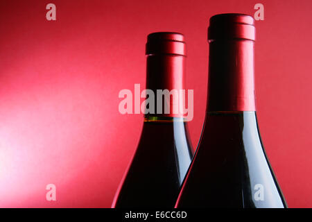 Zwei verkorkten Weinflaschen auf rotem Grund Stockfoto