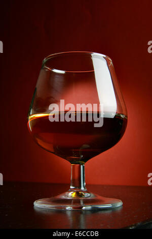 Glas Cognac Nahaufnahme über tiefroten Hintergrund Stockfoto