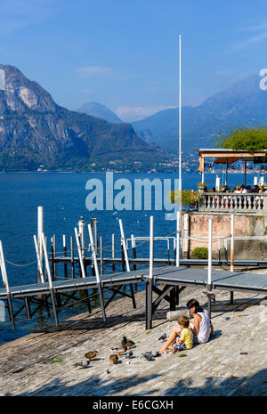 Mutter und junge Sohn füttern, Enten und Tauben an der Seepromenade in Bellagio, Comer See, Lombardei, Italien Stockfoto