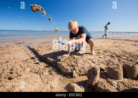 Ein Junge, bauen eine Sandburg am Strand von Bamburgh, Northumberland, UK. Stockfoto