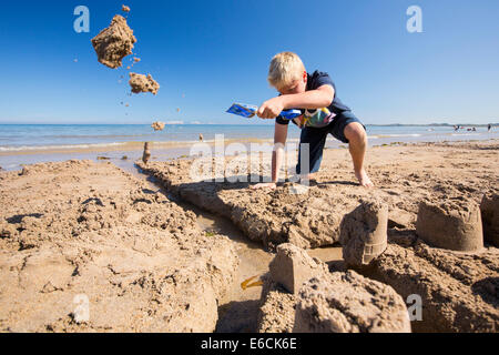 Ein Junge, bauen eine Sandburg am Strand von Bamburgh, Northumberland, UK. Stockfoto