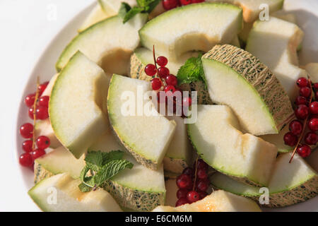 Melone mit roten Johannisbeeren schneiden Stockfoto