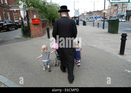 Orthodoxer chassidischer jüdischer Vater, der mit Familienkindern und Kinderwagen durch die Stadt läuft Stoke Newington, Hackney London, Großbritannien KATHY DEWITT Stockfoto