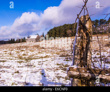 Eine Scheune befindet sich in einem teilweise schneebedeckten Feld. Stockfoto