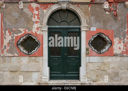 Altes Haus mit läutenden Putz, grünen Türen und schmiedeeisernen bedeckt geometrischen Fenster auf Insel Burano in Lagune. Stockfoto